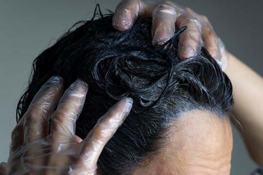 Closeup Woman Hands Dyeing Hair. Middle Age Woman Colouring Dark Hair With Gray Roots At Home