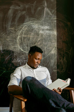 Businessman reading book against scribble wall