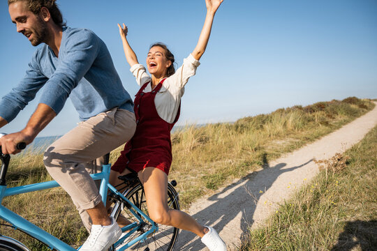 Carefree woman enjoying bicycle ride with man against clear sky