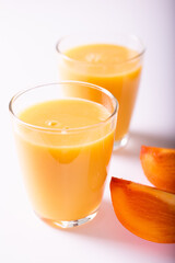 healthy persimon juice in glasses on white with two pieces of fruite at foreground