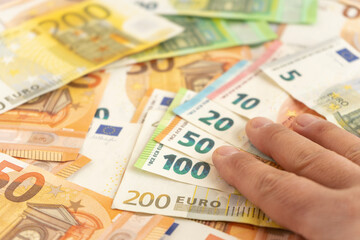 A close-up of a businessman's hands shows several bills of different denominations. The businessman's hand shows the banknotes from highest to lowest