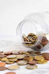 Euro coins spilling out a money jar shot on white background. Predominant colors are bronze and white.