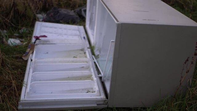 Refrigerator dumped in countryside field isolated shot