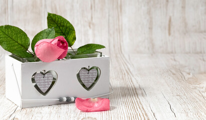 Pink rose in a white box. Two hearts on a box. Wooden gray background. Wedding background. Valentine's Day. Postcard. Copy space.