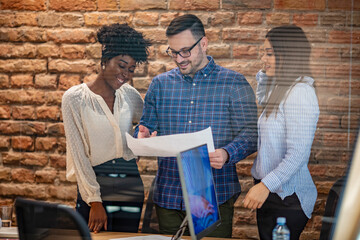 Full concentration at work. Group of young business people working and communicating while sitting at the office desk together with colleagues sitting in the background