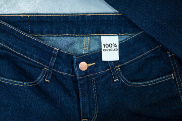 Recycled blue jeans with a clothing tag inside. Circular economy principle, zero waste concept....