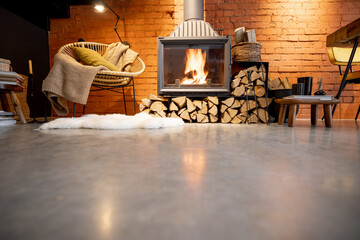 Cozy fireplace with firewood in the loft style home interior with brick wall background, burning...