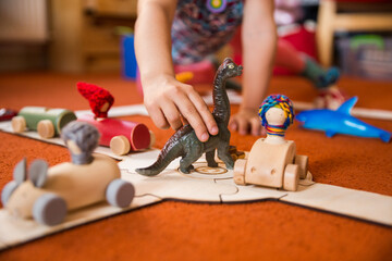Hands of a child playing with wooden toys at home. Colorful interior of a children's room.