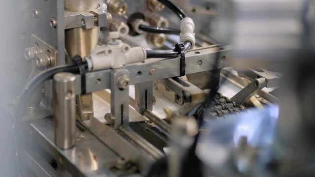 White cardboard sheet moving fast on conveyor line of automatic carton box making machine at food package exhibition, trade show - close up. Industrial, equipment, technology concept