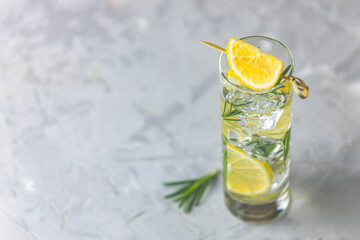 Refreshing lemon lime drink with ice cubes in glass goblets against a light gray background. Summer fresh lemon soda cocktail with rosemary, selective focus