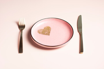 Valentine's Day table setting, pink plate with golden heart on powdery background, horizontal...