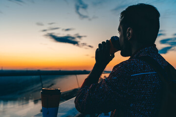 the man on the bridge drinks coffee and faces the dawn