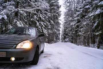 Car on a snowy road going into the distance in the forest