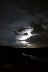 Strong lightning in and behind big towering thunderclouds
