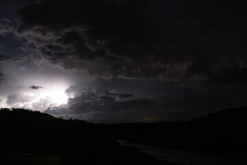 Strong lightning in and behind big towering thunderclouds