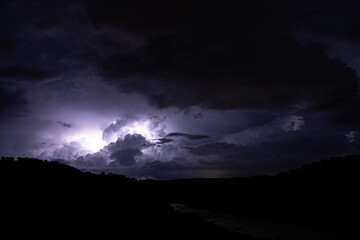 Strong lightning in and behind big towering thunderclouds