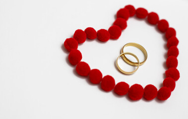 Gold wedding rings in red heart. Wedding rings on the white background, surrounded by the heart. Symbol of love and devotion