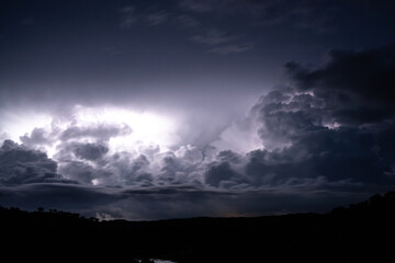 Strong lightning in and behind big towering thunderclouds