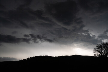 Strong lightning in and behind big towering thunderclouds