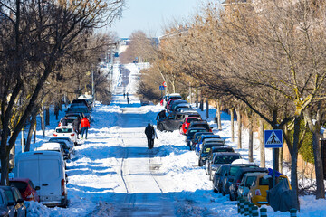 PANORÁMICA DE CALLE DE MADRID CUBIERTA DE NIEVE POR TEMPORAL DE FRÍO Y PERSONAS ANDANDO SOBRE LA...