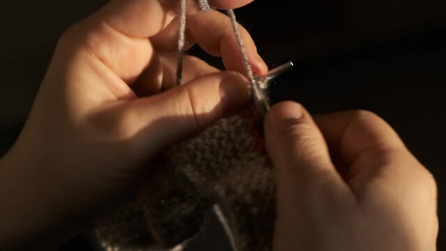 knit a woolen sweater for the winter with knitting needles. close-up of woman's hand doing knitting.