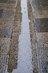 Wet and slippery outdoor cityscape stone floor with raindrops falling on it on a rainy scene
