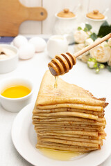Honey is poured onto thin pancakes. Traditional dessert for Shrovetide.