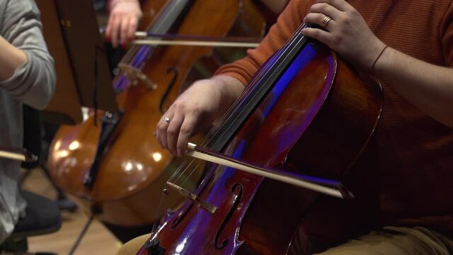 Symphony orchestra violin. Female cello player playing violoncello. Close up of woman hand playing cello. Cello player playing cello bow. Orchestra musicians instruments