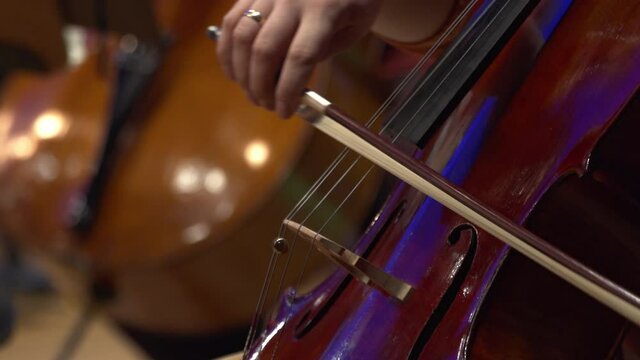 Symphony orchestra violin. Female cello player playing violoncello. Close up of woman hand playing cello. Cello player playing cello bow. Orchestra musicians instruments