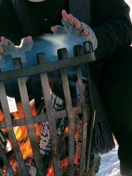 close up of hands wearing winter gloves warming up over the flames in a fire bowl