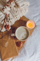 Home cozy decor. A mug of cappuccino, cookies, a candle on the bed. Winter morning.