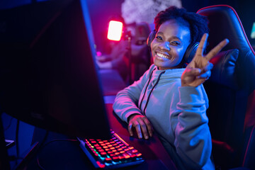 Happy Streamer African young woman professional cyber gamer online video games computer, dark color - obrazy, fototapety, plakaty