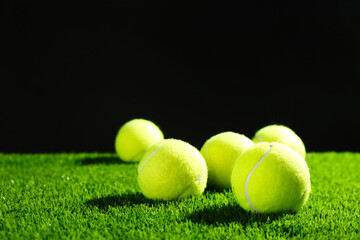 Tennis balls on green grass against dark background. Space for text