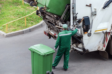 garbage collector loads garbage truck with household waste from garbage cans
