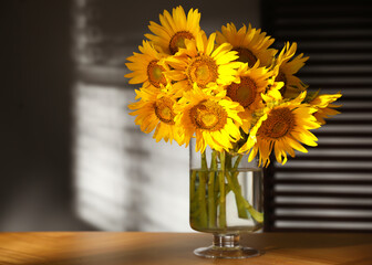 Bouquet of beautiful sunflowers on table in room. Space for text