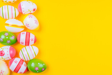 Fototapeta na wymiar Colorful easter painted eggs background on yellow pastel color background with space. Easter holiday concept. Traditional decoration for springtime holiday. Top view easter greeting card.