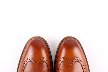 Cropped shot of a pair of light brown double monk strap shoes isolated on white background. Versatile business casual dress shoes without laces. Top view, copy space for text, flat lay.