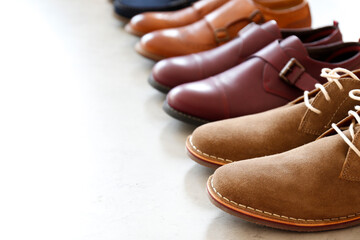 Bunch of different style men's shoes in a row isolated on white background. Close up shot chukka...