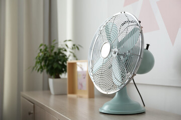 Fototapeta Modern electric fan on wooden table indoors, space for text. Summer heat obraz