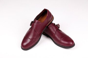A pair of burgundy single monk strap shoes isolated on white background. Versatile business casual dress shoes without laces. Top view, copy space for text, flat lay.