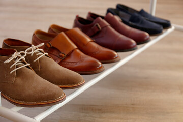 Bunch of different style men's shoes in a row. Close up shot chukka boots, single and double monk strap oxfords, brown, black and burgundy brogues. Top view, copy space, flat lay, wooden background