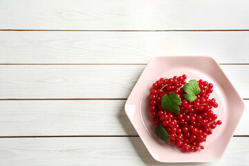 Delicious red currants and leaves on white wooden table, top view. Space for text