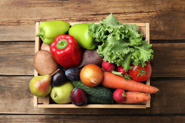 Crate full of different vegetables and fruits on wooden table, top view. Harvesting time