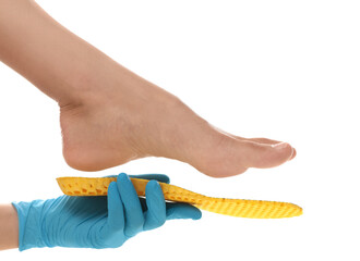 Orthopedist fitting insole on patient's foot against white background, closeup