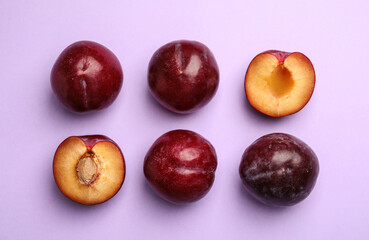 Delicious ripe plums on violet background, flat lay