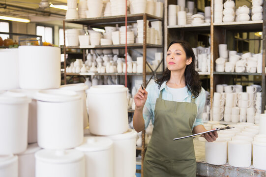 Woman with checklist in pottery warehouse