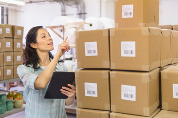 Woman counting boxes in warehouse
