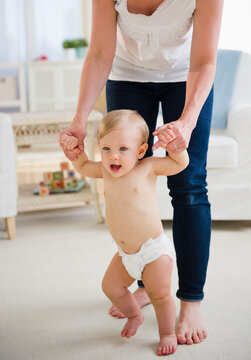 Baby boy (6-11 months) walking with mother