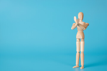 Photo of wooden male figure demonstrating crossed hands isolated blue background with copy space