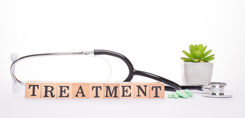 Treatment getting concept. Panoramic banner close up view photo image of doctor stethoscope heap of green tablets plant and wooden blocks making word treatment isolated white desk